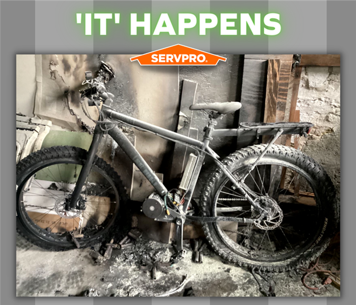Electric bike with fire damage and SERVPRO logo over grey striped background
