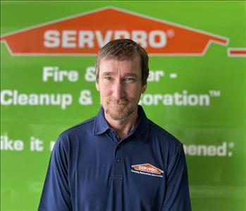 Man in blue polo in front of SERVPRO truck